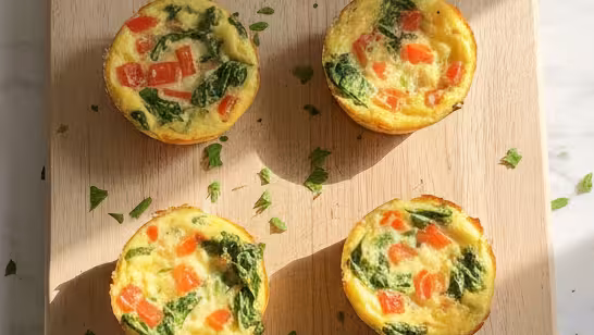 A top-down view of the best veggie egg white cups on a rustic wooden board, ready for a healthy breakfast.